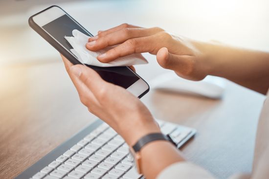 persona limpiando pantalla de celular con toallita húmeda